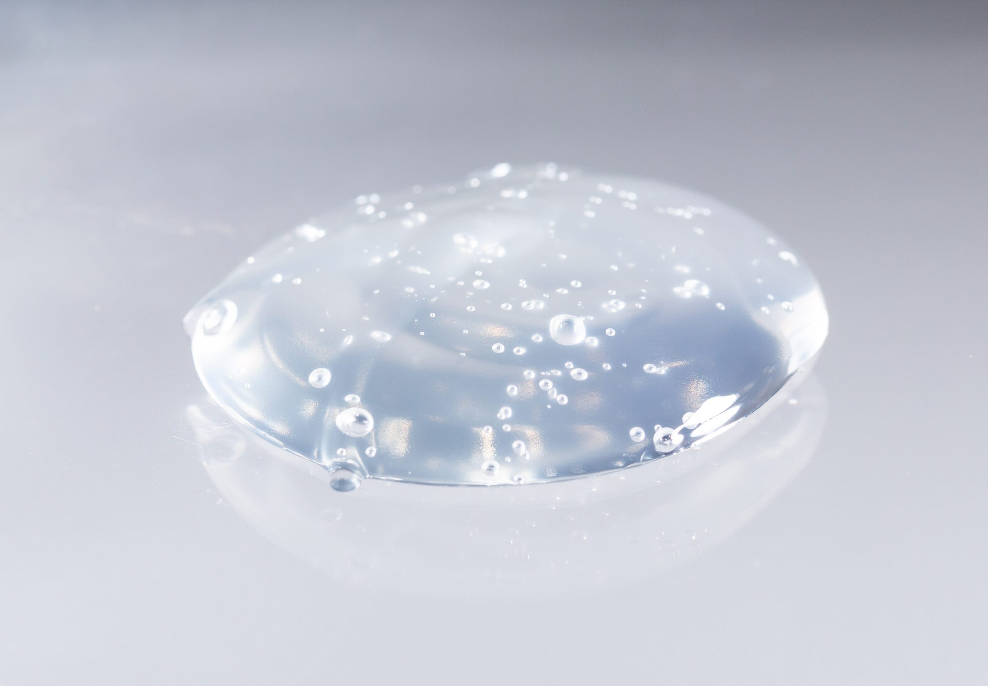 グレーの背景に置かれた、気泡を含んだ透明でみずみずしいジェルのテクスチャー写真