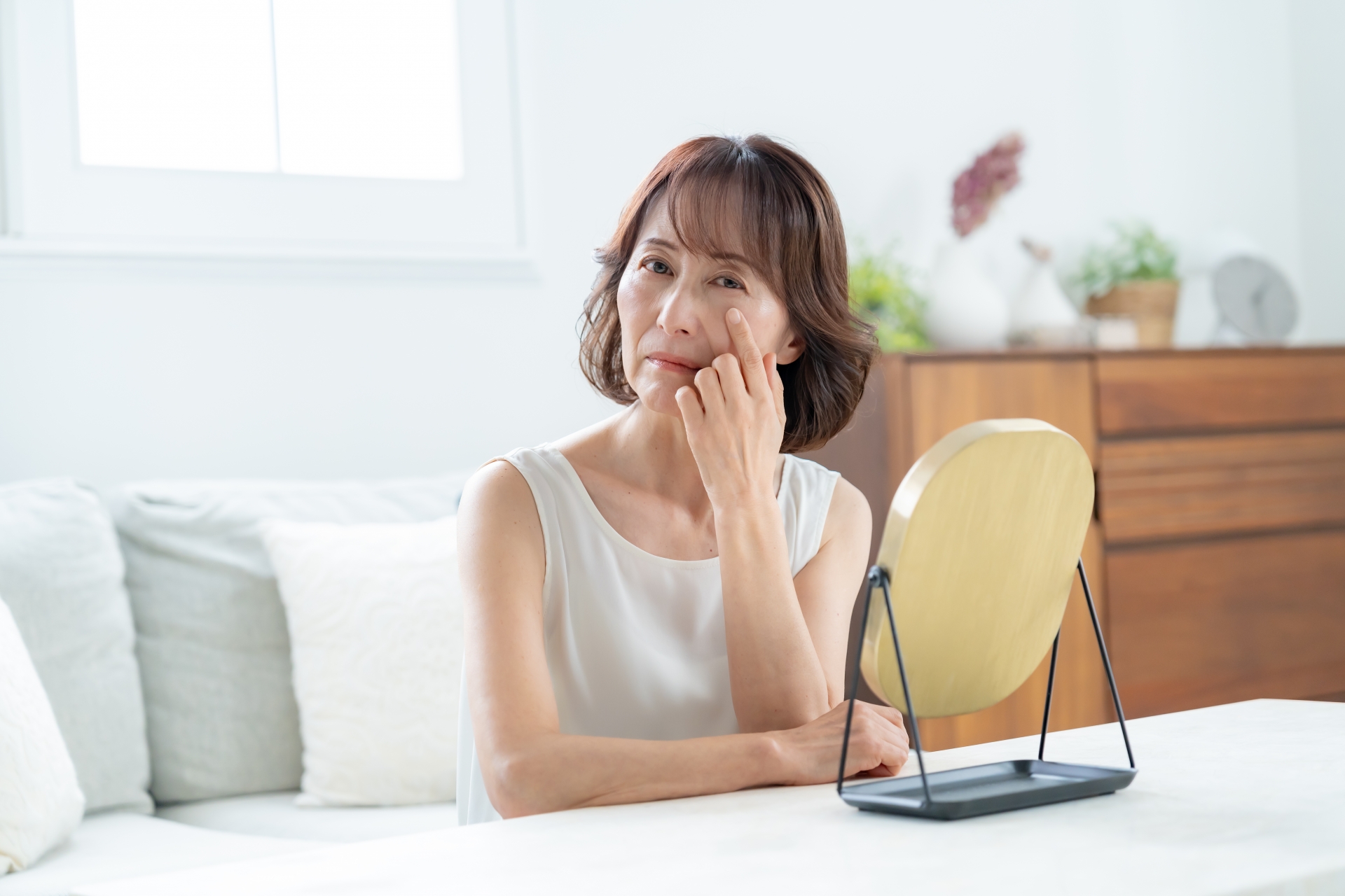 年齢にともなうお肌の変化や目元をチェックする女性