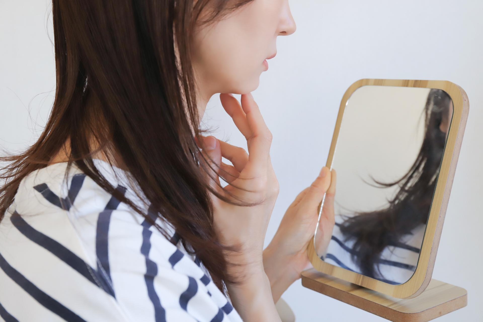 鏡を見ながら自分の肌悩みを確認する女性