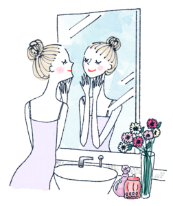 洗面台の鏡の前で、笑顔で肌のお手入れをするお団子ヘアの女性のイラスト。