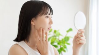 鏡を見て肌の状態を確認する女性
