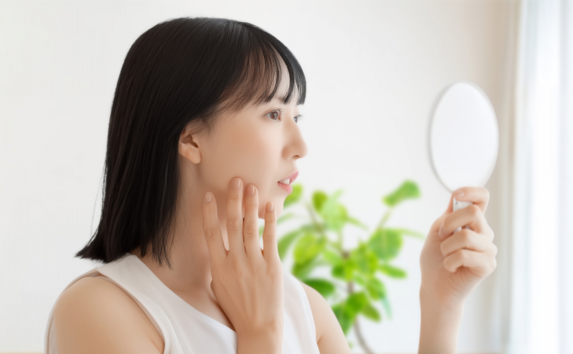 鏡を見て肌の状態を確認する女性
