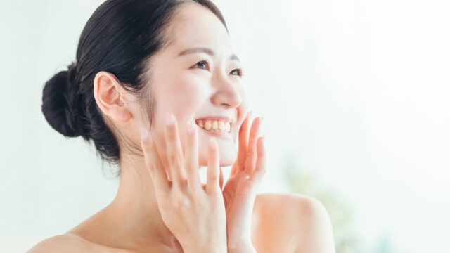 スキンケアの基本ステップを実践し、ハンドプレスで肌の潤いを確認する女性