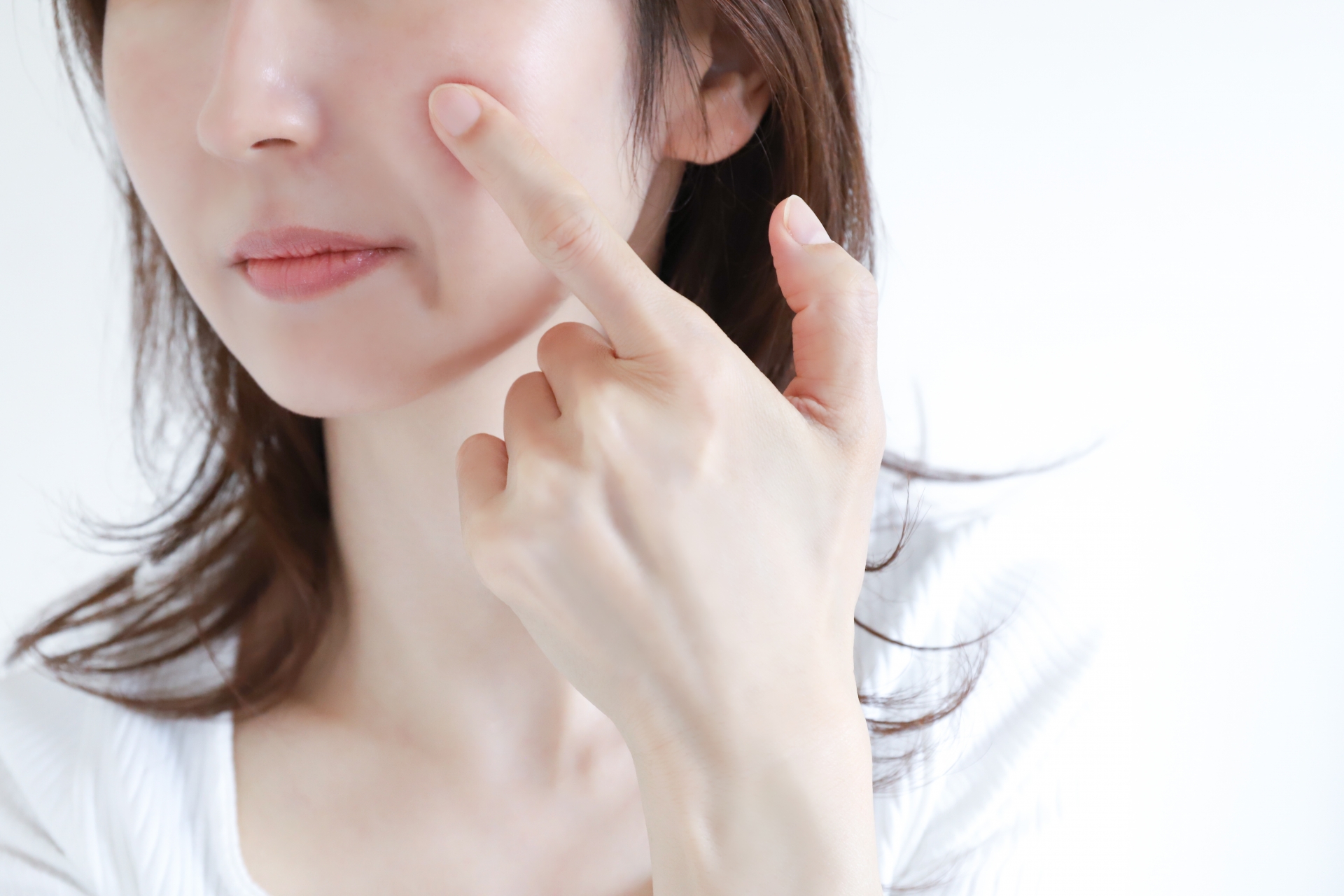 指で頬に触れて肌の潤いやコンディションを確認する女性