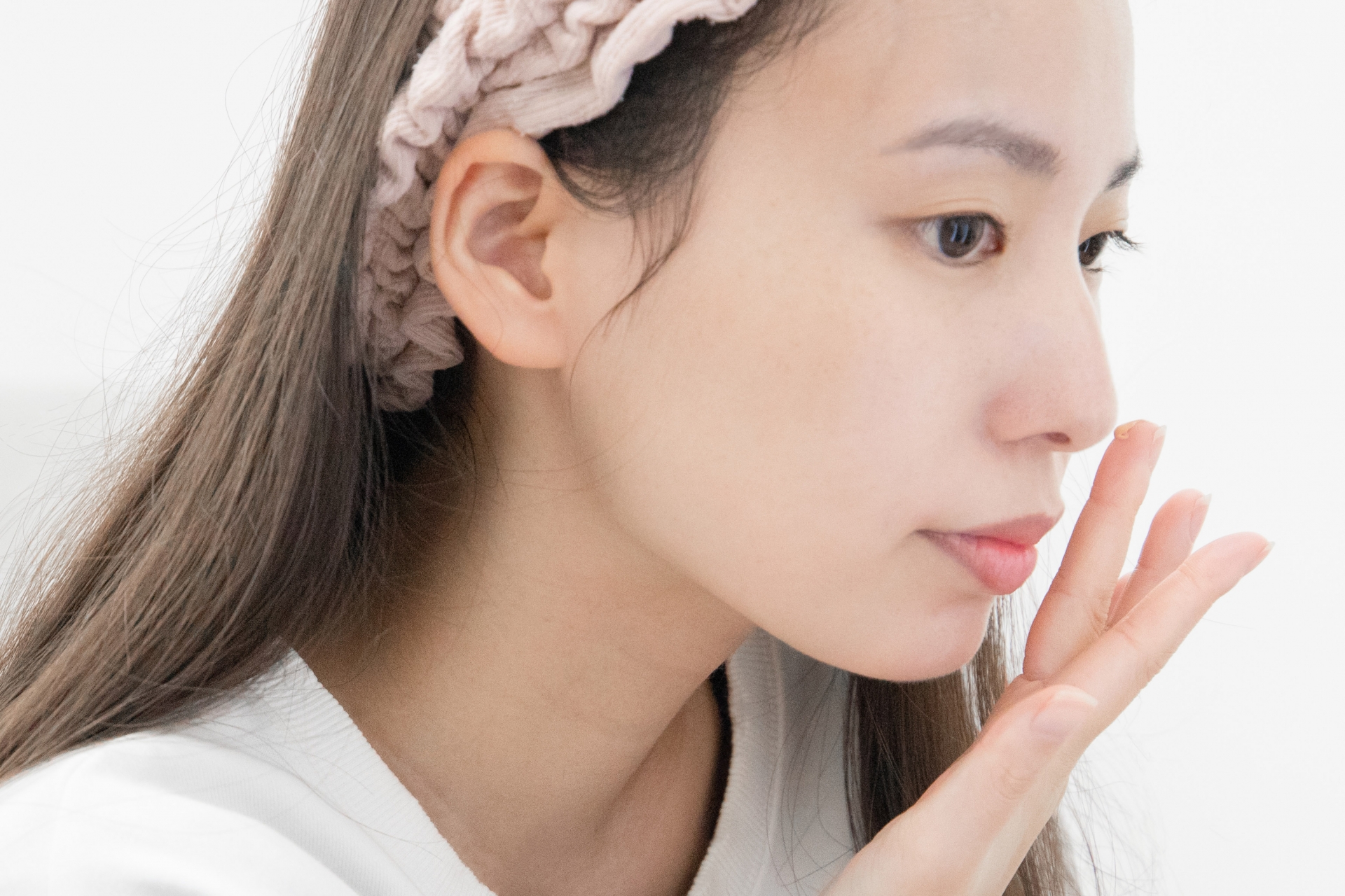 顔に指で丁寧にクリームをなじませる女性の横顔