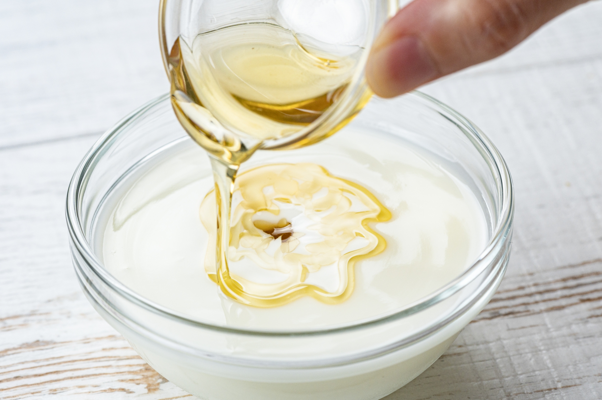 ボウルに入った真っ白なヨーグルトに、黄金色のはちみつを回しかける様子