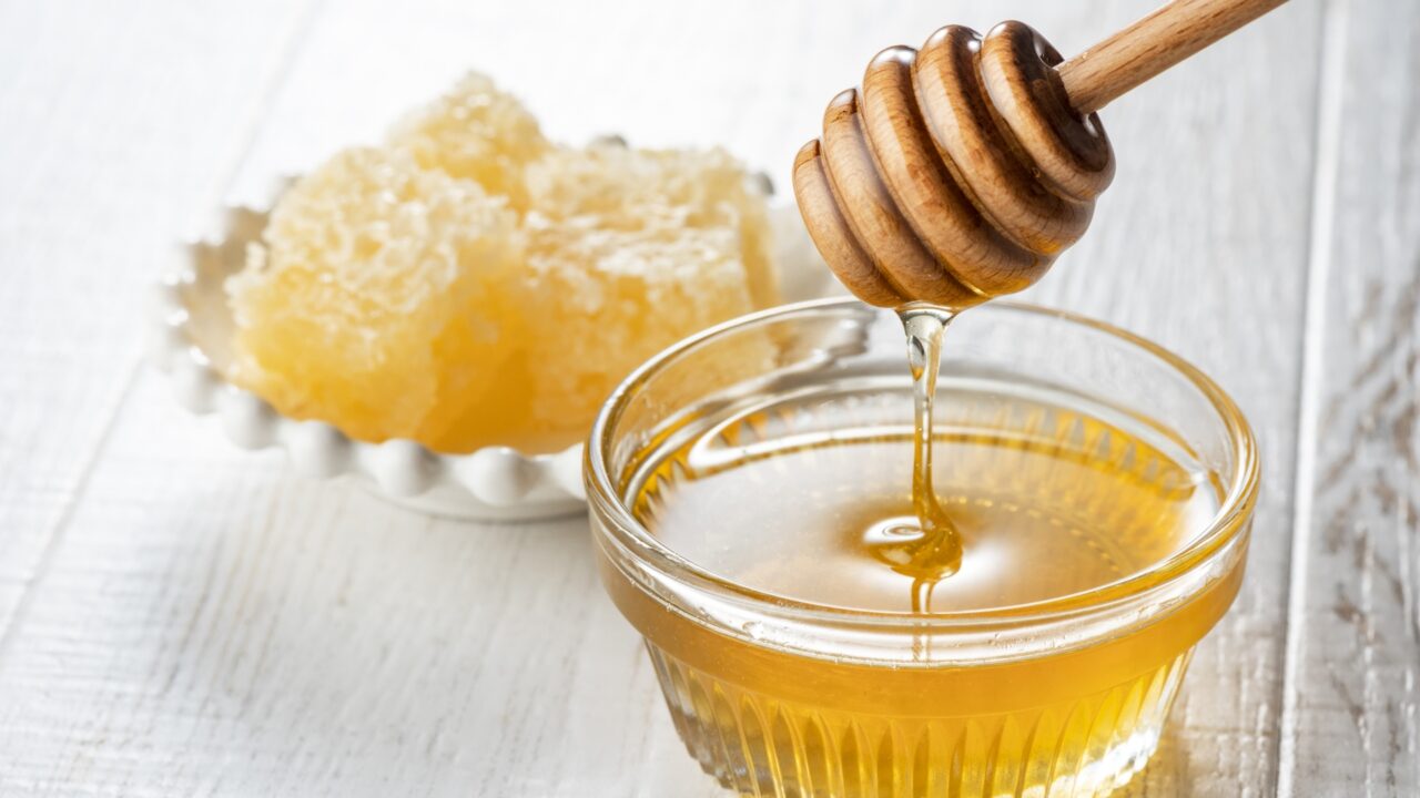 ガラス容器に入ったはちみつと、巣蜜（ハニカム）が添えられた画像