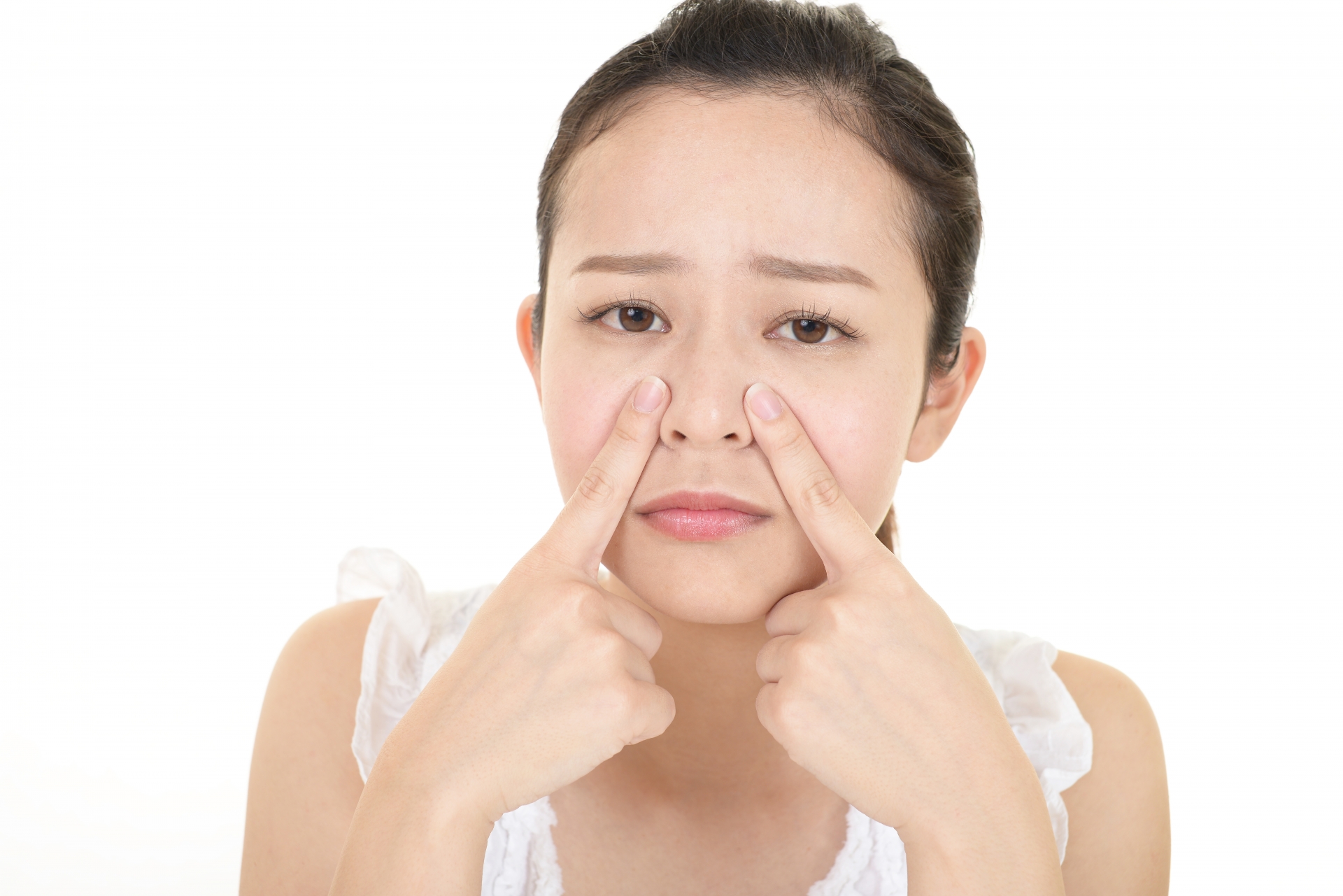 小鼻を指先で強く押し、毛穴の状態を気にする女性