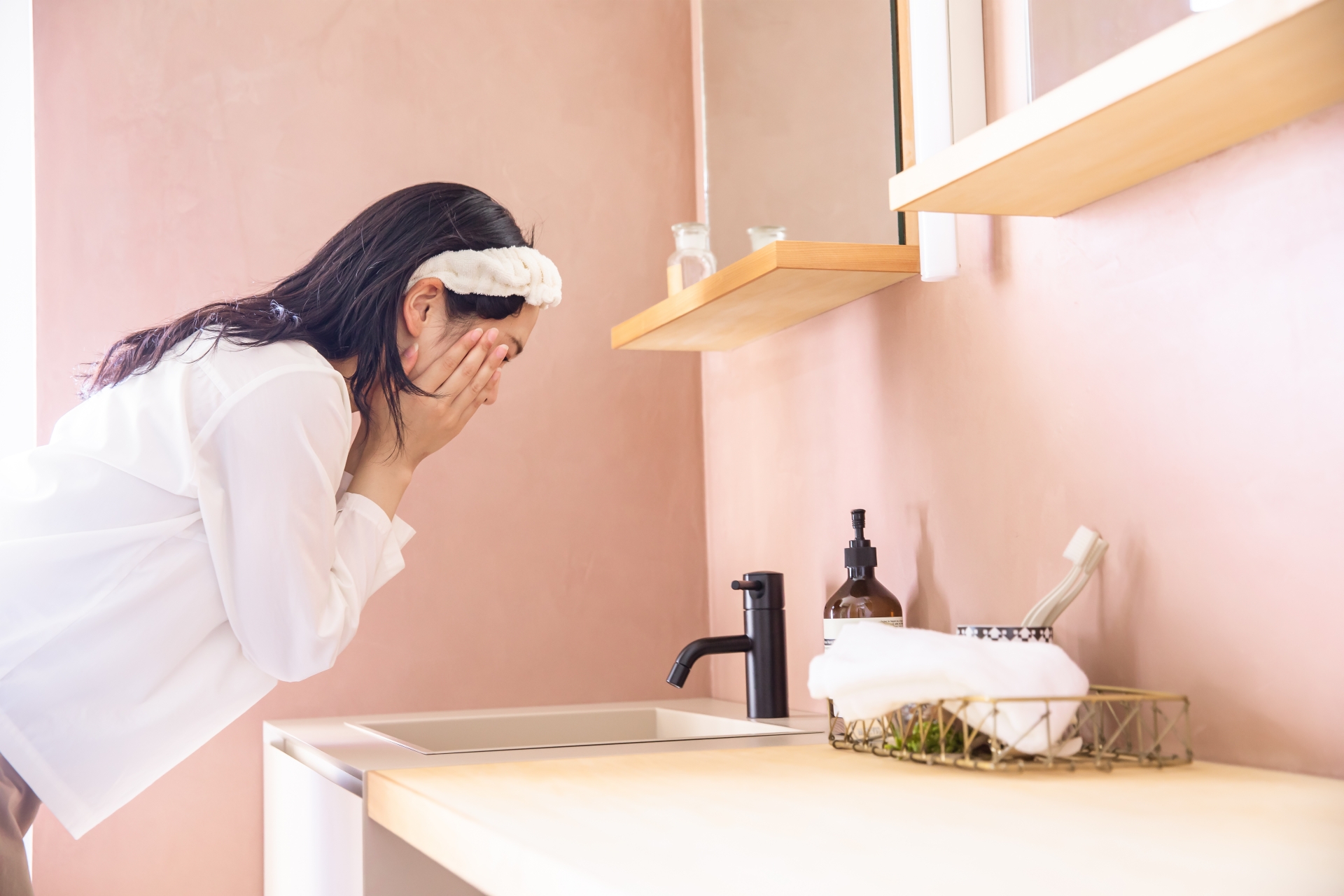 洗面台で肌のケアを自力で行う女性。自宅で実践できる正しいスキンケアのイメージ
