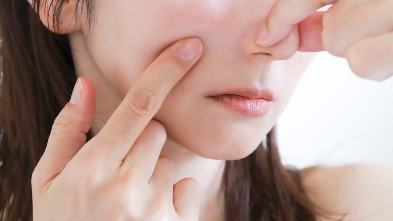 指で鼻や頬を押し、角栓や毛穴の状態を気にしている女性