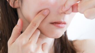 指で鼻や頬を押し、角栓や毛穴の状態を気にしている女性