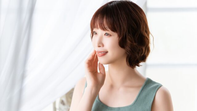 自分の素肌に触れて微笑む女性。