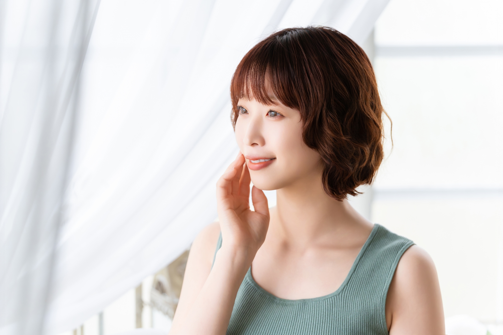 自分の素肌に触れて微笑む女性。