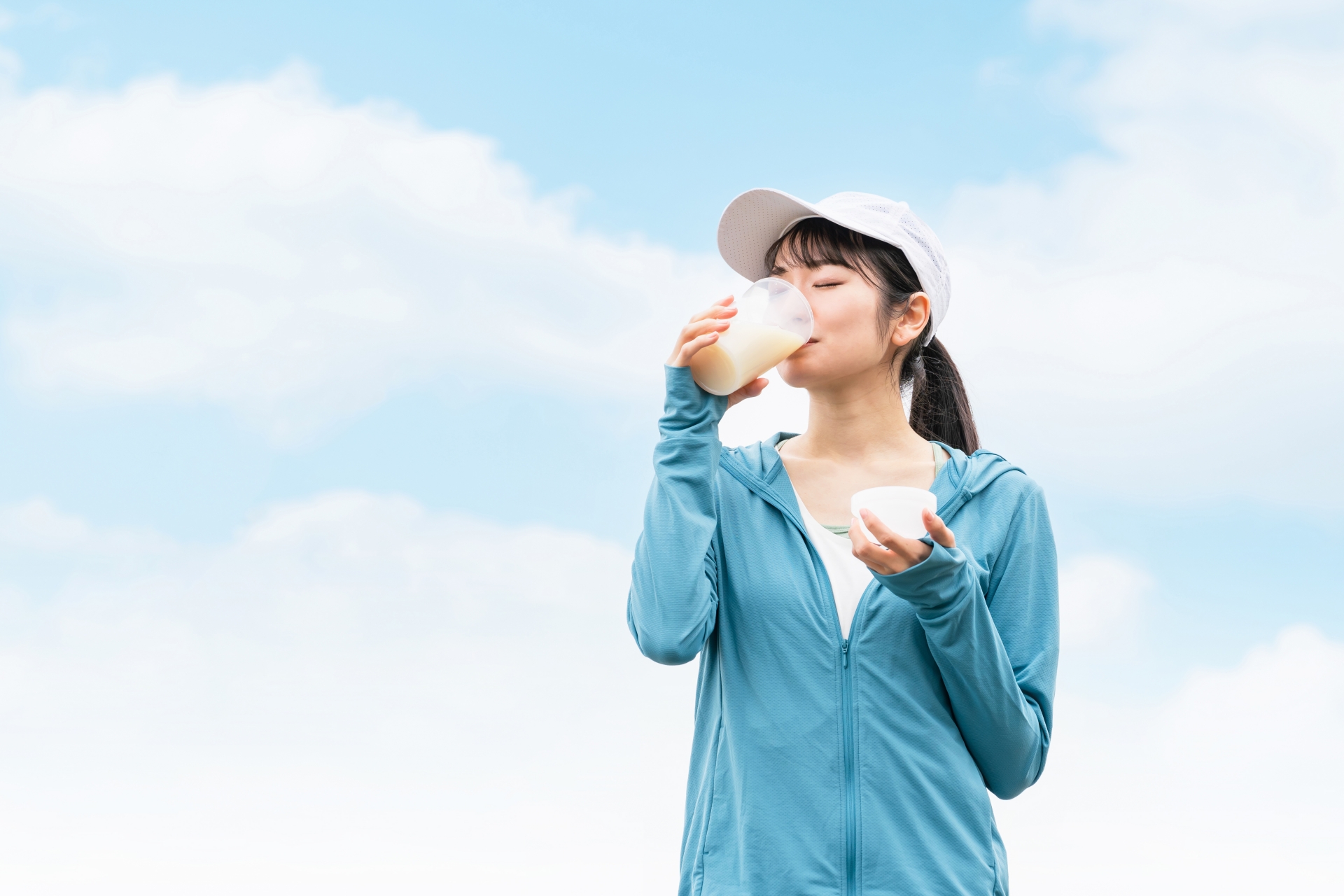 屋外でプロテインドリンクを飲み、健康的な習慣を実践している女性の姿。