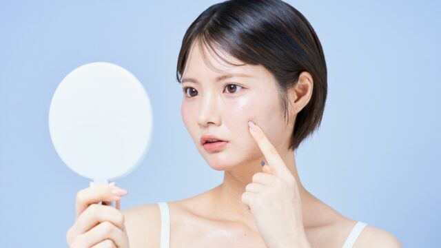 鏡を見ながら、気になる肌の乾燥やつっぱりを確認している女性の顔のアップ