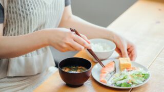 焼き鮭や卵焼き、具だくさんの味噌汁など、免疫力アップにつながる栄養バランスの良い和食を食べる風景の写真。