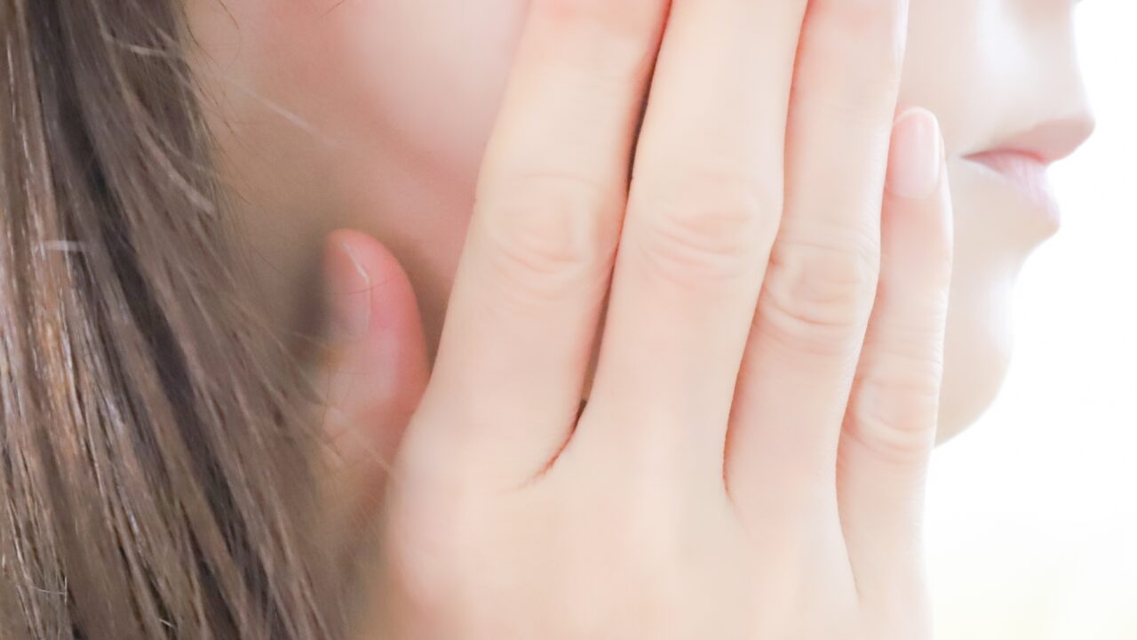 自分の頬に手を添えて肌の状態を確認する女性