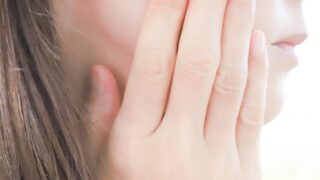 自分の頬に手を添えて肌の状態を確認する女性