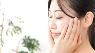 両手を頬に添えて穏やかな表情で目を閉じている女性