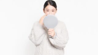 自分の肌状態を鏡でチェックする女性