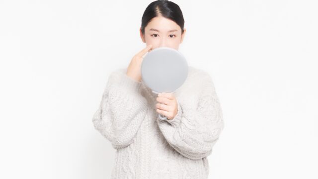 自分の肌状態を鏡でチェックする女性