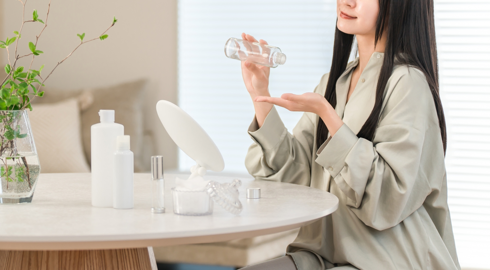 透明な容器から手のひらに化粧水をとる女性
