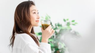 毎日の美容ケアやインナーケアをイメージさせる、グラスに入った青汁を持つ女性